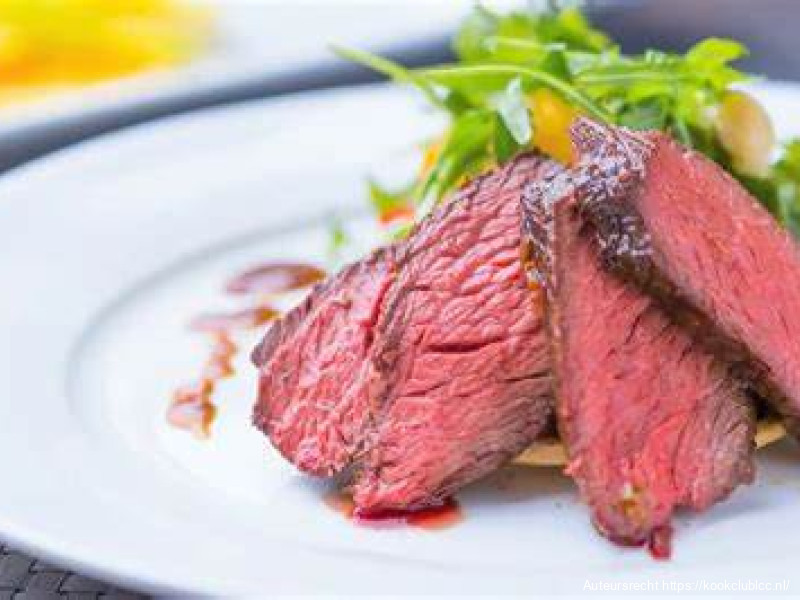 Kangaroesteak met rozijnensaus en een salade van gegrilde groenten.