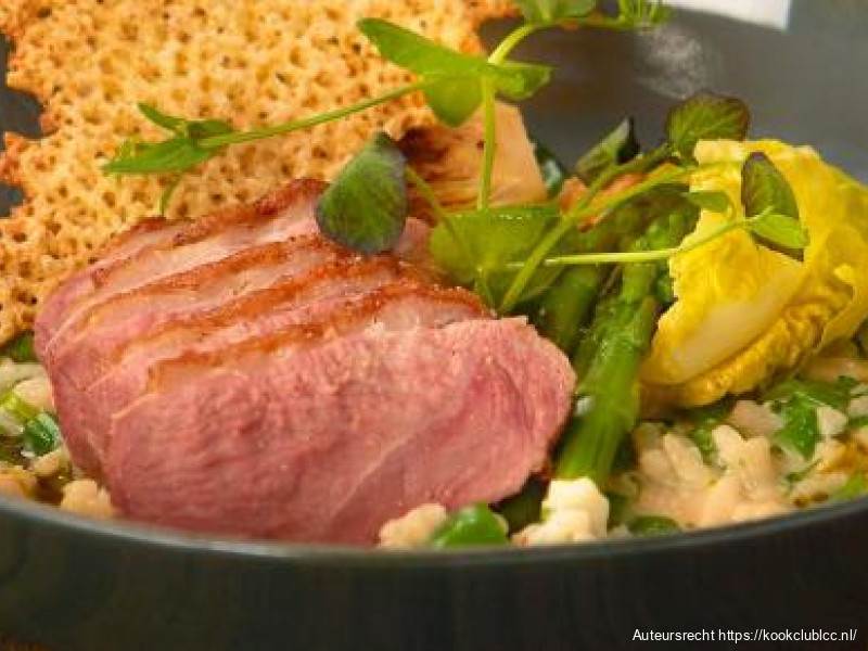 Risotto met eend, groene groenten, een saus van crème de cassis en een krokantje van Parmezaanse kaas
